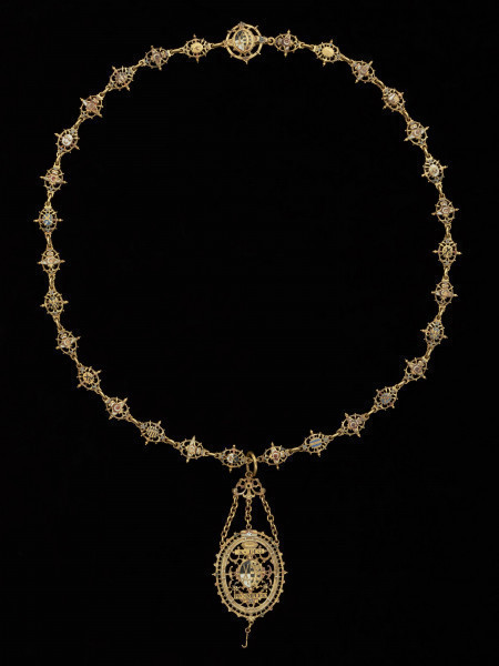 odznaka honorowa elektora saskiego Jana Jerzego I - Ujęcie odznaki z przodu z łańcuchem. Odznaka o owalnym kształcie, ażurowa, emaliowana. Jej głównym elementem jest czarny dwugłowy orzeł w koronie cesarskiej. Na awersie, na piersi orła herb Saksonii Elektorskiej. W owalnej ramce, otoczonej rucianym wieńcem inskrypcja: SVB. VMBRA. ALARUM. TUARUM.1.6.11. Na rewersie na tułowiu orła wieniec z kwiatkami trzymany przez dwie dłonie. W otoku napis: PRVS. MOR. QVAM. FIDEM. FALLIERE. U dołu szczątkowo zachowana perła. Odznaka przy pomocy trzech łańcuszków połączona jest z ażurową plakietką z uszkiem. Łańcuch składa się z dziesięciu owalnych ogniw z emaliowanymi herbami prowincji saskich (różnymi po obu stronach). Między nimi ogniwa z motywem dłoni trzymających zielony wieniec z białymi kwiatkami, a także gładkie okrągłe ogniwa i ogniwa o fakturze plecionki. Na emaliowanej, kolistej zapince motyw dwugłowego orła z herbem Saksonii Elektorskiej.