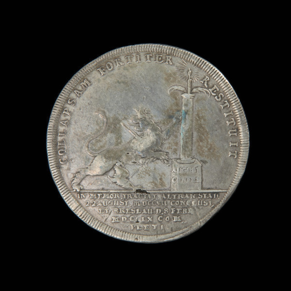 talar okolicznościowy - Ujęcie rewersu. Na rewersie ukoronowany lew kroczący w prawo. Głowa odwrócona do tyłu, w prawej łapie miecz, lewa oparta o kolumnę, na której gałązki palmowe i płonąca świeca. Na trzonie kolumny napis. W otoku napis. W odcinku napis w pięciu wierszach.