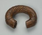 biżuteria, bransoleta - Ujęcie z przodu z góry. Otwarta, miedziana, owalna bransoleta ozdobiona grubymi, zaokrąglonymi, biegnącymi dookolnie prążkami; cienkimi, ukośnymi nacięciami oraz półkolami przypominającymi wachlarze wyłaniające się z motywu plecionki.