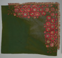 zielona chusta z, haftem z motywami kwiatowymi, cekinami i frędzlami - Ujęcie z przodu; Chusta kwadratowa, z wełnianej, ciemnozielonej tkaniny, zdobiona haftem płaskim z motywem wielopłatkowych kwiatków w kolorze czerwonym, ułożonych w trzech rzędach, jeden nad drugim, w rzędzie dolnym kwiatki mniejsze. Środki kwiatów o kolorach niebieskim, żółtym i zielonym układają się w różne wzory florystyczne. Każdy z kwiatów obwiedziony jest złotym sznureczkiem. Pomiędzy większymi dodatkowo wyhaftowane są drobniejsze kwiatki. całość zdobiona także cekinami. Pomiędzy kwiatami w rogu napis: 