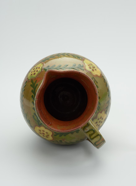 Gliniany dzban zdobiony motywem kwiatowym - Ujęcie wnętrza.. Dzban gliniany. Wlew okragły ze spiczastym dziobkiem. Wewnatrz brązowa glazura, na zewnatrz zielona.