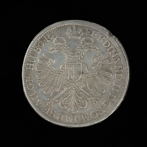 talar Rzeszy - Ujęcie rewersu. Na rewersie monety putto trzymające dwie owalne barokowe tarcze herbowe z wielkim i małym herbem Norymbergii, powyżej owalna tarcza herbowa z orłem króla rzymskiego dzieląca datę: 16 - 35, napis w otoku i znak mincerski.