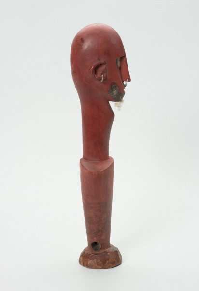 lalka teatralna Ton Fa (opiekun/patron męskiej części Kamalen Ton) - Ujęcie z prawej strony. Figurka z drewna pomalowana na kolor czerwony, przedstawiająca postać męską  z długą szyją i odstającymi uszami. Nos długi, wąski, na końcu z przymocowaną na wylot metalową cienką obręczą. Oczy blisko nosa, z przymocowanymi metalowymi blaszkami. Krótka broda z jasnego włosia. Korpus w formie stożka odwróconego dnem do góry. Zamiast nóg okrągła mała podstawa. Nad nią, na środku wywiercony na wylot niewielki otwór.