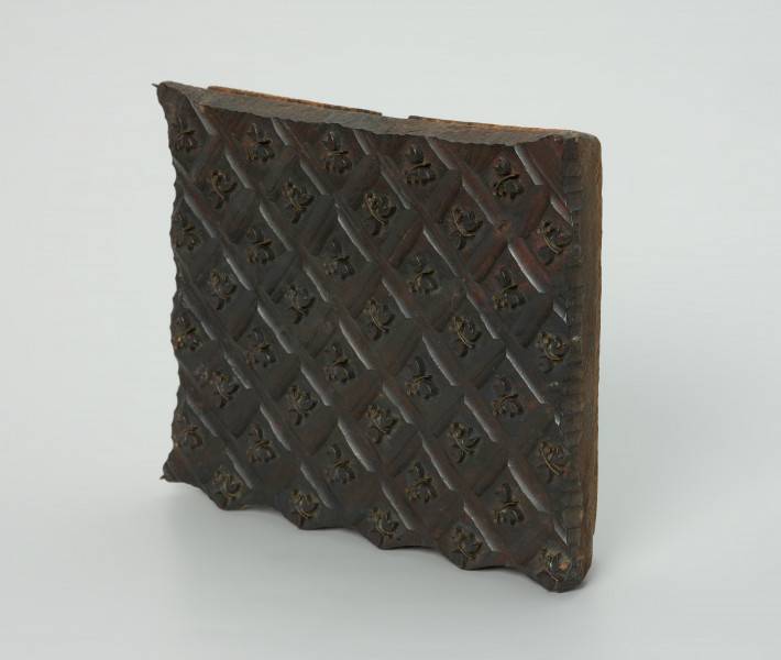 sprzęt do drukowania i grafiki, matryca drukująca - Ujęcie przodu skosem w prawą stronę. Matryca do drukowania tkanin z wykonanym częściowo w drewnie i częsciowo z mosiężnych sztyfcików i blaszek w nie nabitych, ornamencie o motywie roślinnym.