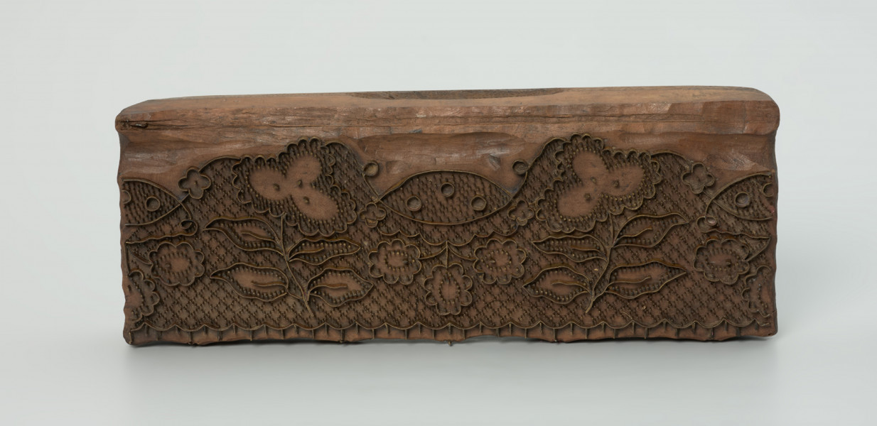 sprzęt do drukowania i grafiki, matryca drukująca - Ujęcie z przodu w pionie. Matryca do drukowania tkanin z wykonanym z nabitych w drewno mosiężnych sztyfcików i blaszek ornamentem naśladującym koronkę siatkową.