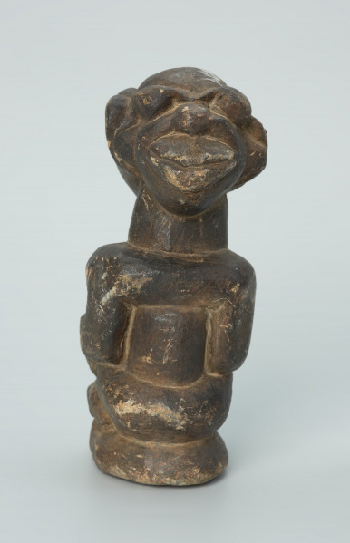 rzeźba; przedmiot obrzędowy; Figura kultu sił wegetacji - Ujęcie z tyłu. Rzeźbiona w grafitowym steatycie siedząca postać ludzka o dwóch twarzach, z przodu i z tyłu głowy.