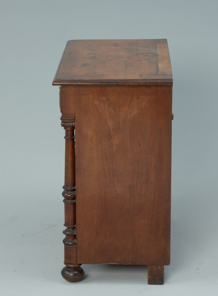 szafka - Ujęcie z prawego boku. Szafka w typie bieliźniarki z drewna fornirowanego, przeznaczona pod lustro, dwudrzwiowa z szufladą górną.