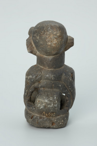 rzeźba; przedmiot obrzędowy; Figura kultu sił wegetacji - Ujęcie z tyłu. Rzeźbiona w grafitowym steatycie półpostać o cechach ciężarnej kobiety. W dużym, wydętym brzuchu z czterema otworami umieszczona jest kamienna kula.