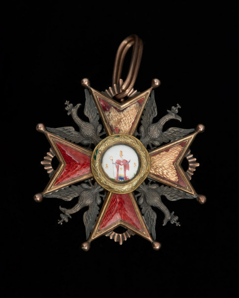 Order Świętego Stanisława I klasy - Ujęcie awersu. Na awersie między ramionami krzyża maltańskiego cztery srebrne orły. W tarczy środkowej, obwiedzionej wieńcem laurowym postać świętego Stanisława w stroju biskupim, z pastorałem w ręku. Po obu stronach postaci litery SS (Sanctus Stanislaus). We wcięciu ramion motyw promienisty, w górnym podłużna zawieszka.