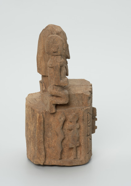 drewniane pudełko na fetysz - Ujęcie prawego boku. Drewniane pudełko, dekorowane płaskorzeźbami, w środku którego widoczne są drzwiczki.