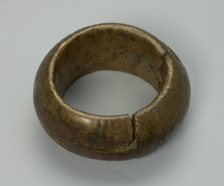 biżuteria, bransoleta - Ujęcie z tyłu z dołu. Dwuczęściowa, mosiężna, kulista bransoleta składająca się z dwóch wkładanych, półkulistych elementów. Zewnętrzna powierzchnia ozdobiona punktowym wzorem w postaci pionowych i ukośnych linii, kół oraz półkoli. Brak wzoru na bocznym grzebiecie.