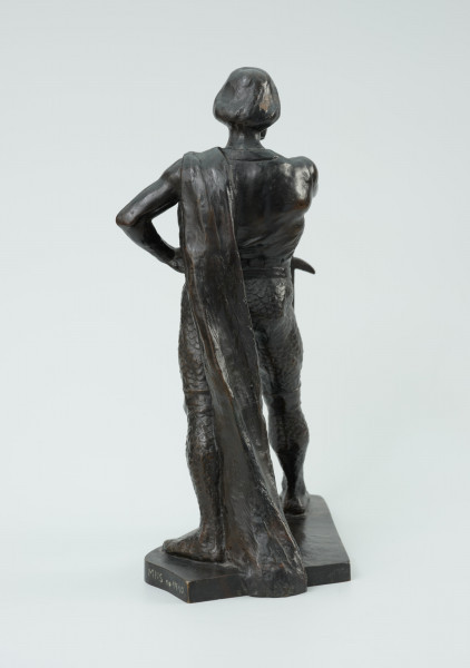 posąg - Ujęcie z tyłu; Postać mężczyzny w postawie kroczącej. Wyciągnięta do przodu prawa ręka wsparta na mieczu. Wysunięta w prawo noga dotyka zakończenia ostrza miecza. Lewa ręka zgięta, dłoń wsparta na biodrze. Przez lewe ramię przewieszona draperia której zwój opada za lewą nogą do podstawy. Twarz pociągła, silnie zarysowane łuki brwi, usta okolone opadającym wąsem. Rozczesane gładko włosy.