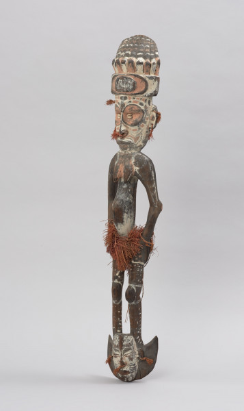 hak do wieszania toreb - Ujęcie ze skosu z lewej; Drewniany hak z postacią ludzką (najprawdopodobniej kobietą) w górnej części i kotwicowym zaczepem z wyrzeźbioną głową ludzką w dolnej części. Hak polichromowany, bogato zdobiony