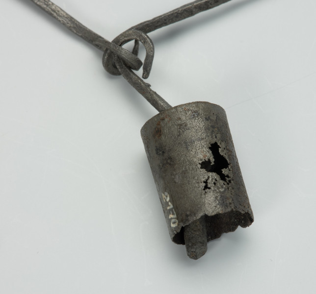 przedmiot ceremonialny, przedmiot religijny i obrzędowy, fetysz - Ujęcie drugiego detalu. Łańcuch składający się z licznych, połączonych ze sobą żelaznych ogniw. Rozdwaja się na końcu tworząc literę Y. Ozdobiony pierścieniami z podwójnym wisiorkiem o trapezowatym kształcie, kamiennym i żelaznym paciorkiem oraz otwartym, żelaznym walcem.