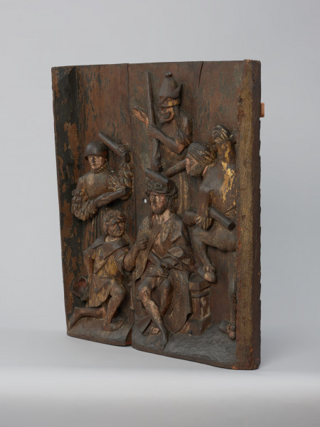 sztuka sakralna, kwatera ołtarza, płaskorzeźba - Ujęcie ze skosu z prawej strony; Płaskorzeźba przedstawiająca Cierniem Koronowanie. Żołnierze oprawcy otaczają skazanego na śmierć Chrystusa i kijami wciskają koronę cierniową na Jego głowę. Kwatera lewego skrzydła późnogotyckiego ołtarza pasyjnego z Wkryujścia (Ueckermünde).