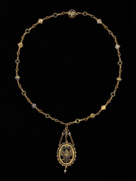 odznaka honorowa elektora saskiego Christiana II - Ujęcie całej odznaki z łańcuchem z tyłu. Odznaka o owalnym kształcie, ażurowa, emaliowana. Na awersie pośrodku tarcza migdałowa z elektorskim herbem dzielonym. W otaczającym ją ornamencie na dwóch tabliczkach dewiza: A DEO / PRO IMPERIO. Nad inskrypcją oko opatrzności. Na rewersie w środkowym polu motyw słońca w otoczeniu sześciu gwiazd. Na tabliczkach inskrypcja: „TIME DEUM / HONORA CAESAREM”. U dołu zawieszenia sztyft będący pozostałością po perle. Odznaka przy pomocy trzech łańcuszków połączona jest z ażurową plakietką z uszkiem. Łańcuch składa się z 30 ozdobnych, ażurowych, emaliowanych ogniw, połączonych kółkami ze złotego drutu. Na połowie z nich ukazano emaliowane herby 15 prowincji saskich. Na pozostałych 15 przedstawiono serce z literą C i kapeluszem elektorskim, trzymane w dwóch dłoniach. Na kolistej zapince emaliowany herb elektorskiej Saksonii.