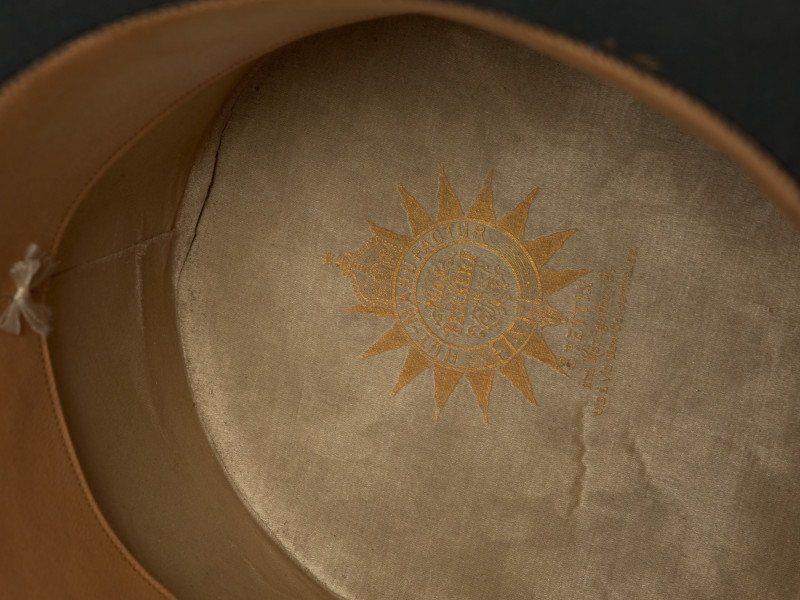 czarny cylinder z welurowej tkaniny - detal; ujęcie wnętrza; Wewnątrz skórkowy otok. Emaliowana literka 