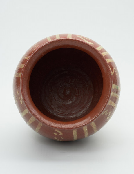 naczynie zasobowe - Ujęcie wnętrza. Bezuche naczynie wykonane z gliny techniką toczenia na kole. Średnica wylewu większa od średnicy dna. Największe rozszerzenie brzuśca powyżej połowy wysokości naczynia. Kołnierz wyraźnie zaznaczony, wygięty. Zewnętrzna powierzchnia naczynia oraz kołnierz pokryte brązowoceglastą polewą oraz szkliwem. Brzusiec ozdobiony pionowym ornamentem geometrycznym – powtarzający się motyw grup trzech pasków oddzielonych zygzakowatymi liniami.