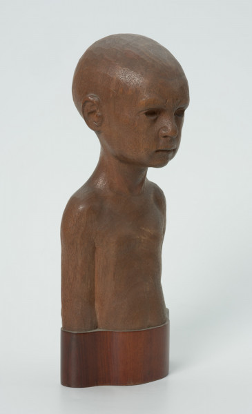 portret dziecięcy - Ujęcie z przodu skosem w prawą stronę; Wyrzeźbione w drzewie mahoniowym popiersie dziecka, chłopczyka. Ogolona głowa, oczy blisko siebie, smutne usta. Przedstawiony jest kilkuletni syn artysty.