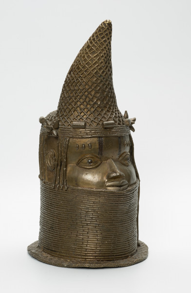 Głowa Królowej Matki - Ujęcie z przodu z prawej strony. Brązowy, pusty w środku odlew głowy kobiety, o złotym zabarwieniu. Twarz o cechach negroidalnych, wydatnych, lekko rozchylonych ustach oraz szerokim u nasady nosie ma oczy z wyraźnie zaznaczoną linią powiek. Na ich wysokości usytuowane są nieduże uszy. Lekko wypukłe czoło dekorowane jest pionowymi inkrustacjami z żelaza oraz trzema podłużnymi, symetrycznie rozmieszczonymi, pogrubieniami nad każdym okiem. Szyję i podbródek do wysokości dolnej wargi zasłonięto masywnym naszyjnikiem z korali. Głowa jest nienaturalnie poszerzona w tylnej części, tuż pod przechyloną do przodu koroną o charakterystycznym kształcie dziobu papugi, którą nad uszami ozdobiono dwoma rozetami. W dolnej części korony widnieje pięć ozdób o walcowatej formie, trzy nad czołem, dwie za rozetami oraz opaska z korali. Tuż za koroną znajduje się duży, owalny otwór na rzeźbiony kieł słonia, którego brak. Poniżej, po obu stronach twarzy i z tyłu głowy, zaznaczono zaplecione w warkoczyki włosy. Z tyłu głowy pomiędzy włosami a naszyjnikiem usytuowany jest niewielki, okrągły otwór. U podstawy odlewu znajduje się pozioma listwa, dekorowana motywem plecionki.