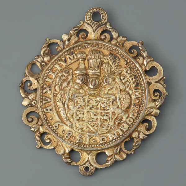 medalion historyczny; medal pamiątkowy - Ujęcie rewersu. Na rewersie dziewięciopolowa tarcza herbowa Pomorza Zachodniego z trzema hełmami i klejnotami, dwa skrajne na głowach leśnych ludzi, którzy stoją zwróceni do tarczy trzymając maczugi. W otoku napis w tłumaczeniu: pomoc dla mnie przyjdzie od Pana. Wokół medalionu ażurowa oprawa o motywach roślinno-wolutowych z dwoma uszkami.