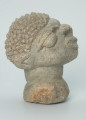 rzeźba; głowa; figura kultu zmarłych - Ujęcie prawy bok. Rzeźbiona w szarobeżowym steatycie, usadowiona na okrągłej podstawce, głowa postaci ludzkiej z dużymi uszami z tyłu i w charakterystycznym uczesani w formie małych, lekko zaokrąglonych stożków, być może loczków.