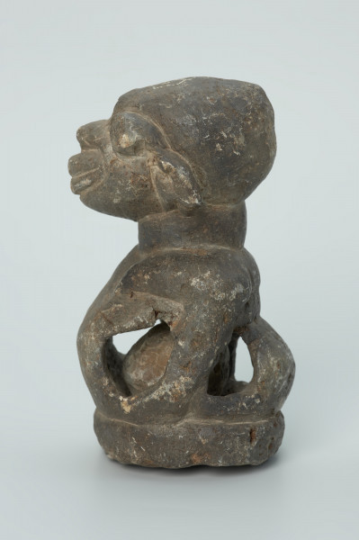 rzeźba; przedmiot obrzędowy; Figura kultu sił wegetacji - Ujęcie lewy bok. Rzeźbiona w grafitowym steatycie półpostać o cechach ciężarnej kobiety. W dużym, wydętym brzuchu z czterema otworami umieszczona jest kamienna kula.
