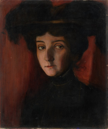 portret kobiecy - ujęcie z przodu; Portret kobiety ujęty w popiersiu. Twarz lekko zwrócona w lewo, wąska, o dużych piwnych oczach, prosto zarysowanych brwiach, wydatnym nosie, małych wąskich ustach. Oświetla ją światło padające z lewej strony. Na głowie duży ciemny kapelusz, ubiór ciemny, wysoko zachodzący na szyję. Tło neutralne. Koloryt: przewaga brązów, czerni.