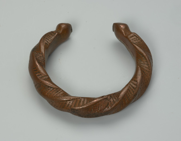 biżuteria, bransoleta - Ujęcie z tyłu z dołu. Otwarta, miedziana, owalna bransoleta pokryta gęstym wzorem punktowym.