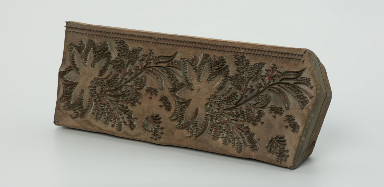 sprzęt do drukowania i grafiki, matryca drukująca - Ujęcie przodu skosem w prawą stronę. Matryca do drukowania tkanin z wykonanym z nabitych w drewno mosiężnych sztyfcików i blaszek ornamentem o motywie roślinnym.