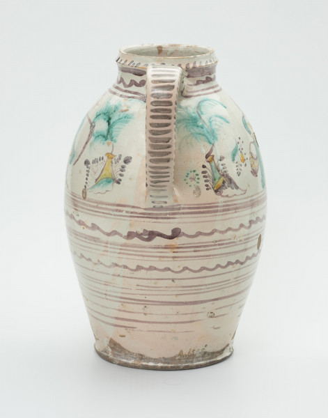 dzban - Ujęcie z tyłu. Dzban uformowany na kole garncarskim z gliny o jasnej barwie ( z małą ilością tlenków żelaza). Dno lekko wyodrębnione, brzusiec kopulasty z bardzo krótką szyjką przechodząca w prosty wlew z kołnierzem. Szyjka i najszersze miejsce brzuśca połączone taśmowym uchem. Dzióbek prosty, krótki wychodzi z górnej części brzuśca. Naczynie malowane ręcznie. Na górnej części brzuśca postać kobiety w długiej zielonej sukni z koszykiem i grabiami w ręce, a po przeciwnej stronie mężczyzna z fajką i kosą, ubrany w zielony surdut i żółte spodnie, włożone w czarne buty z wysoką cholewą. Pomiędzy postaciami wzory kwiatowe. Dolna część brzuśca dekorowana gęsto paskami i liniami falistymi. Szyjka naczynia, ucho i dzióbek zdobione kreskami i paskami. Szyjka dodatkowo zdobiona jest falą. Pod szyjką napis: