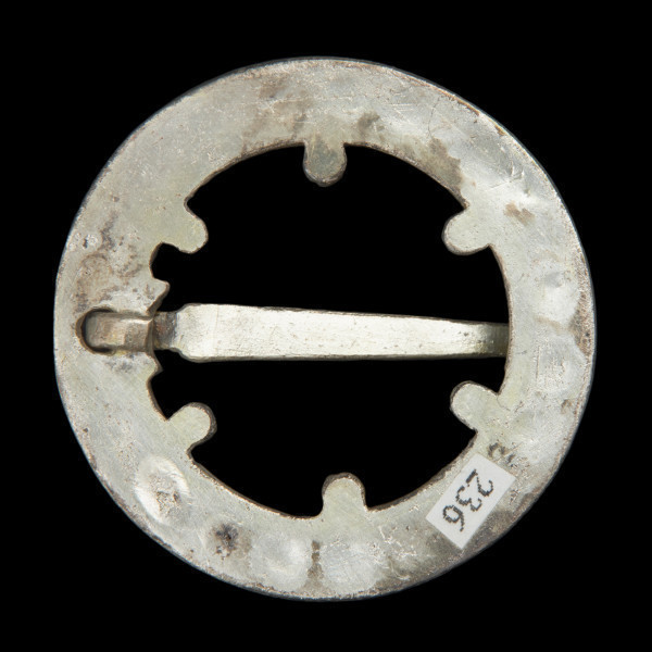 Pozłacana okragła zapinka - Ujęcie z tyłu. Pozłacana okrągła zapinka, z pustym środkiem.. Od spodu gładka powierzchnia. Kolec masywny, zwężający się ku dołowi.