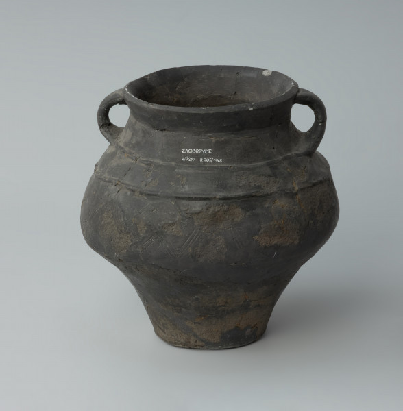 Dwuuche naczynie - Ujęcie z tyłu. Dwuuche naczynie o gładkiej powierzchni barwy ciemnobrunatnej, miejscami czarnej.