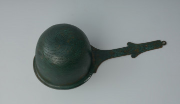 Ujęcie z dołu z prawej strony. Rzymskie cedzidło z brązu z uchwytem zaopatrzonym w woluty.