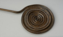 ozdoba stroju; Brązowa szpila - Ujęcie głóki w formie spirali z góry. Brązowa szpila z główkę w formie spiralnej dwunastozwojowej tarczki wykonanej z czworograniastego drutu, natomiast trzpień z okrągłego.