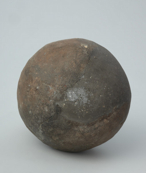 Naczynie gliniane - Ujęcie spodu. Amfora o baniastym brzuścu i cylindrycznej szyjce z parą taśmowatych uch umieszczonych pomiędzy nasadą szyjki i dolną jej partią, zdobiona na szyjce i w górnej części brzuśca trzema dookolnymi pasmami pionowych i ukośnych słupków wykonanych w technice ściegu bruzdowego, rozdzielonych w połowie wysokości szyjki dookolną bruzdą oraz szeroką bruzdą ze śladami wygniatania palcami na przejściu szyjki w brzusiec. Naczynie zrekonstruowane i uzupełnione gipsem barwionym. Barwa od szarobrunatnej do brązowej.