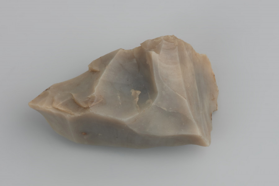 Rdzeń naciskowy podstożkowy - ujęcie z przodu; Rdzeń naciskowy podstożkowy. Pięta rdzenia, czyli powierzchnia, do której przykładano naciskacz, jest płaska, uformowana jednym odbiciem. W końcowej fazie eksploatacji, krótko przed porzuceniem, jeden z boków rdzenia został częściowo odbity kamiennym tłuczkiem. Widoczne są również ślady po różnych zabiegach mających na celu drobne naprawy wierzchołka oraz tyłu rdzenia.