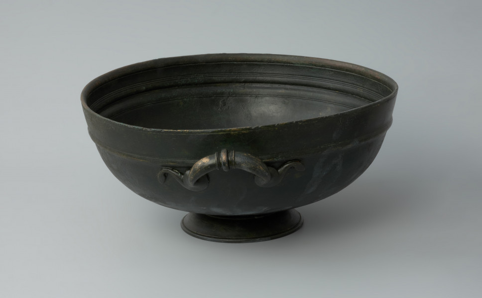 naczynie; Misa z brązu - Ujęcie prawego boku. Misa z brązu na żebrowanej stopce. Na brzuścu znajduje się nieznacznie wypukły wałek.