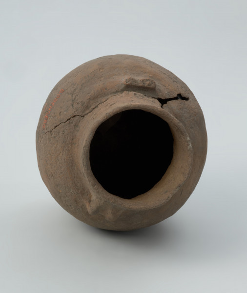 ceramika, naczynie - Ujęcie z góry wnętrza; Niezdobiona amfora z niemal cylindryczną szyjką, z parą taśmowatych, wątorowanych uszek na załomie szyjki i brzuśca. Z kulistym brzuścem i niską stopką. Uszkodzona przy przejściu szyjki w brzusiec (pęknięcie i brak ucha)