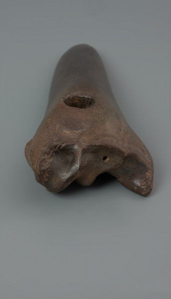 motyka kościana - ujęcie z tyłu; Motyka wykonana poprzez skośne odcięcie trzonu oraz usunięcie części główki kości długiej tura. Poprzeczne ostrze po zewnętrznej stronie jest półokrągłe, od strony ścięcia posiada wgłębienie, pozostałe po ścięciu trzonu i odsłonięciu jamy szpikowej. Okrągły otwór na trzonek przewiercony został poprzecznie do dłuższej osi kości przy główce. Powierzchnia motyki została w znacznym stopniu wyświecona i zagładzona w wyniku użytkowania oraz procesów podepozycyjnych.