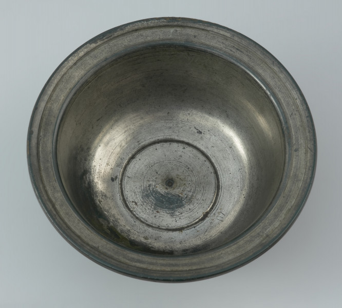 Rzymska miseczka z brązu na stopce - Ujęcie z góry. Rzymska miseczka z brązu na stopce z cylindrycznym brzuścem, szerokim wygiętym na zewnątrz wylewem, posrebrzana wewnątrz.