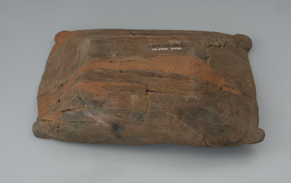 Niecka drewniana; dzieża - Ujęcie spodu. Płytka niecka wydrążona w przepołowionym pniu drzewa liściastego, zaopatrzona w uchwyty ułatwiające przenoszenie