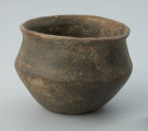 Jasnobrunatne naczynie gliniane o niskiej, przysadzistej formie - Ujęcie z przodu z lewej strony. Jasnobrunatne naczynie gliniane o niskiej, przysadzistej formie.