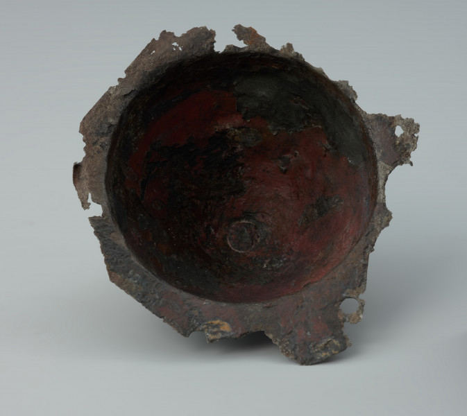 Żelazne umbo ze zniszczonym brzegiem. - Ujęcie z dołu skosem. Żelazne umbo ze zniszczonym brzegiem.