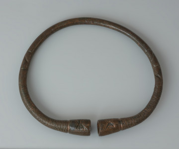 Naszyjnik z brązu - Ujęcie z góry. Naszyjnik z brązu z pogrubionymi zakończeniami, kielichowatego kształtu z zagłębieniami na końcach.