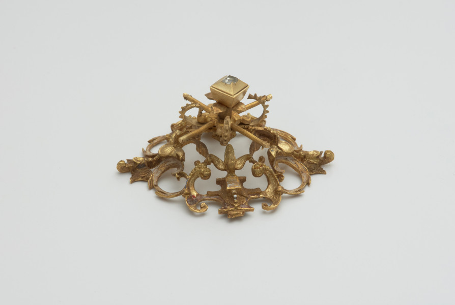 biżuteria, ozdoby - Ujęcie z boku z dołu. Ażurowy klejnot z kołpaka z diamentem i - pierwotnie -czterema perłami, zdobiony barwną emalią.