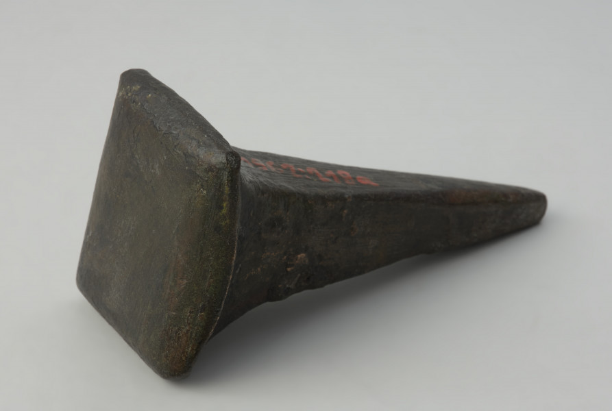 kowadło, narzędzie - Ujęcie w poziomie z tyłu skosem w prawą stronę. Kowadełko brązowe z czworościennym trzpieniem.