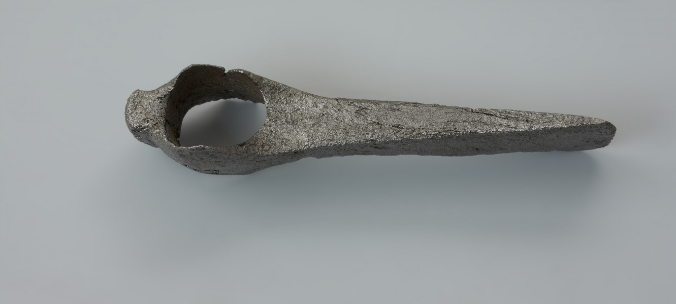 topór bojowy (czekan) - Ujęcie z góry w pionie. Topór ma smukłe żeleźce, prawie prostopadłe w stosunku do osi pionowej toporzyska. Światło osady jest owalne, a sama osada ma zdecydowanie wyodrębnione, nieznacznie zaokrąglone i opuszczone w dół wypustki zwane wąsami. Obuch jest zakończony krótkim, prostokątnym w przekroju zgrubieniem, tzw. młotkiem. Żeleźce topora ma smukłą szyjkę, która łagodnie rozszerza się tworząc wąskie, lekko asymetryczne i łukowate ostrze.