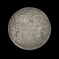 dwutalar medalowy - Ujęcie rewersu. Na rewersie jedenastopolowa tarcza herbowa podtrzymywana przez dwóch dzikich mężów w hełmach z maczugami w rękach. W tle motyw architektoniczny i data 16-35. W otoku kontynuacja napisu z awersu.
