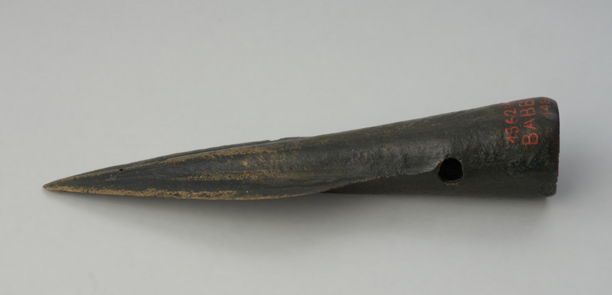 Grot oszczepu - Ujęcie w poziomie tyłu grotu. Brązowy grot oszczepu ma smukłą formę oraz wąski liść. Na tulejce znajdują się dwa otwory na nity.
